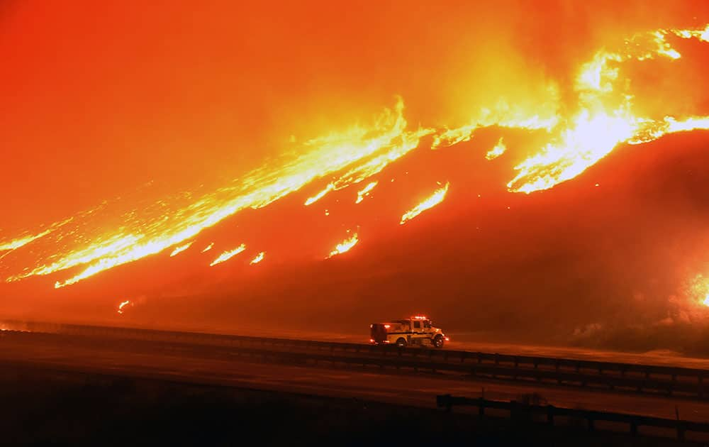 a Ventura County Fire Department engine holds its positions as fire overruns state Highway 101 near Ventura, Calif.