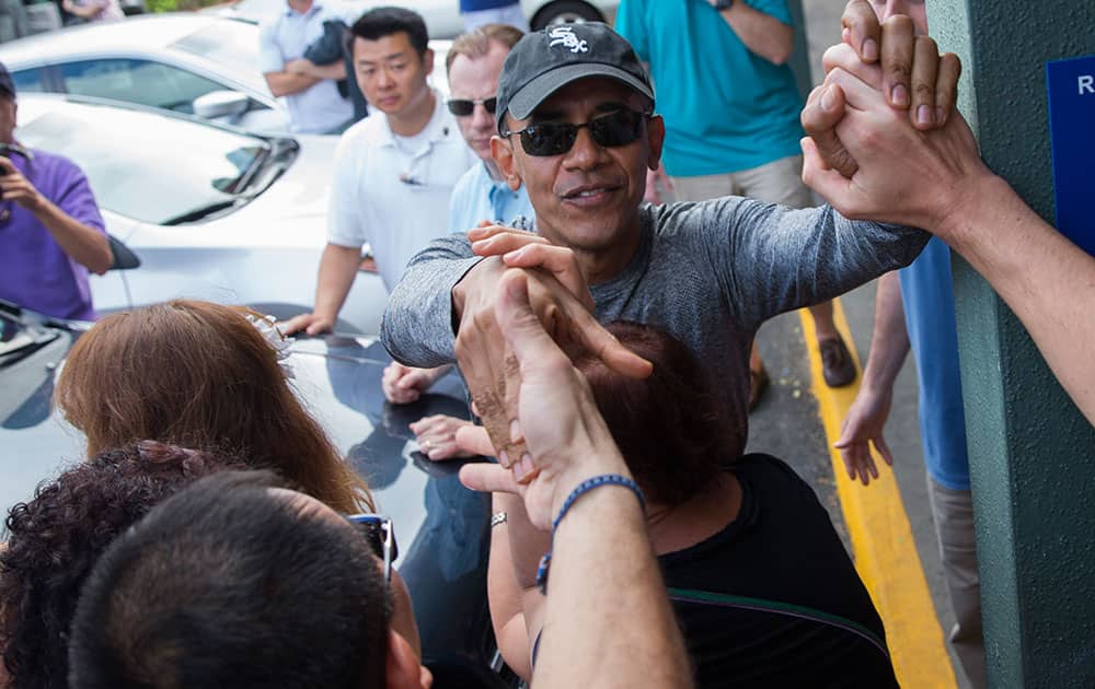 President Barack Obama shakes hands with bystanders during a visit to Island Snow during a family vacation in Kailua, Hawaii. 