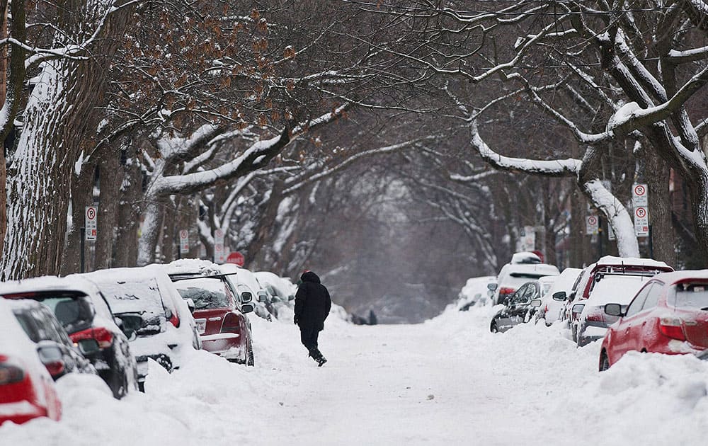 A man walks along a snow covered street in Montreal, following the first major storm of winter in the region. 