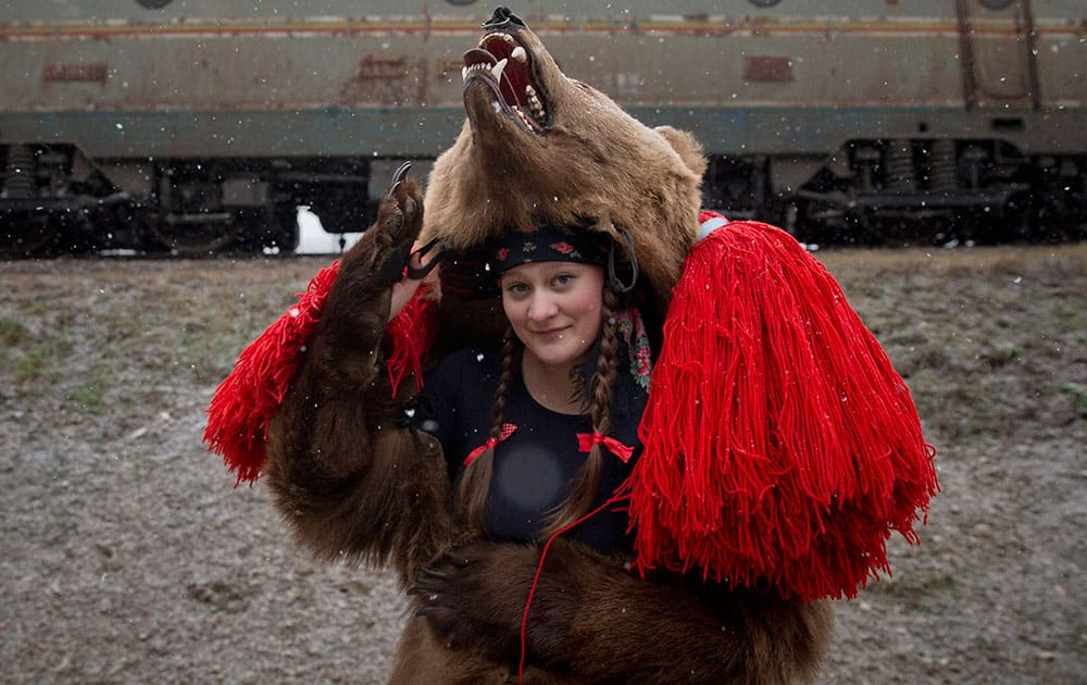 A girl wearing a bear fur poses for a portrait before performing during a festival of New Year ritual dances attended by hundreds in Comanesti, northern Romania.