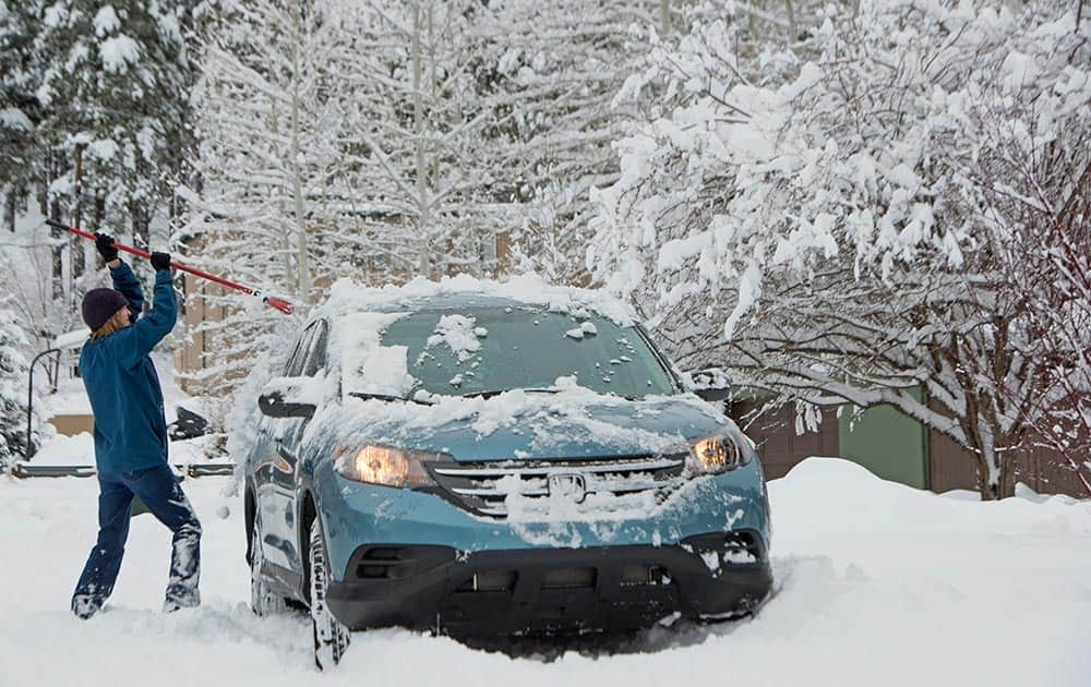 Flagstaff resident Ruth Tilman sweeps off her car after a storm in Flagstaff, Ariz.