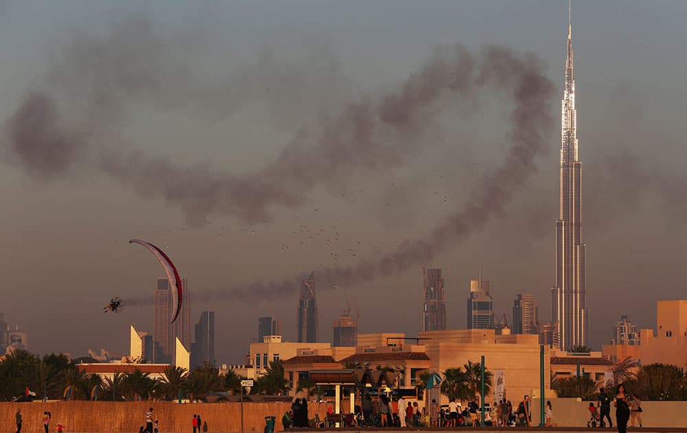 A man in a powered parachute sprays smoke over a crowd with the Burj Khalifa, the worlds tallest building, in the background in Dubai, United Arab Emirates.