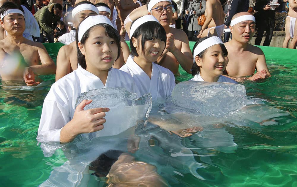 High school students hold blocks of ice as they join other bathers to pray for the healthy new year while dipping in a cold water tub at a park by Teppozu Inari Shinto Shrine during a winter ritual in Tokyo.