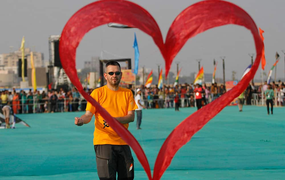 A kite flyer from Switzerland flies his heart shaped kite during international kite festival in Ahmadabad.