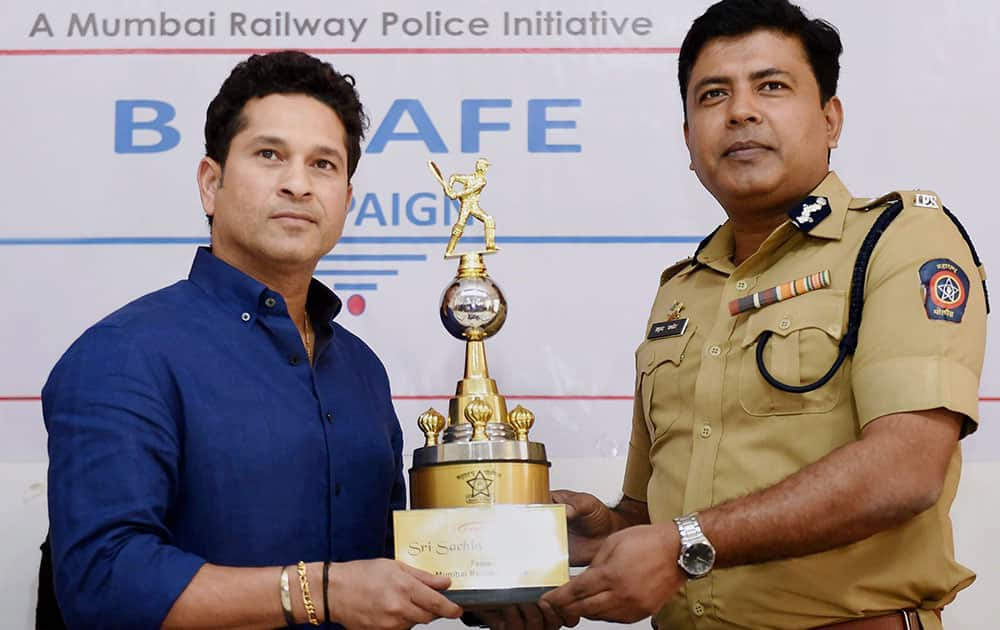 Cricket legend Sachin Tendulkar receives a memento from Railway police commissioner Madhukar Pandey during the launch of a safety campaign for railway commuters, in Mumbai.