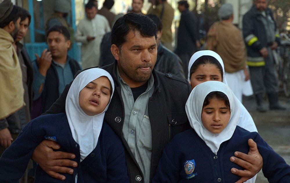 An Afghan man carries two schoolgirls away from a clash site, in Jalalabad, capital of Nangarhar province, Afghanistan.