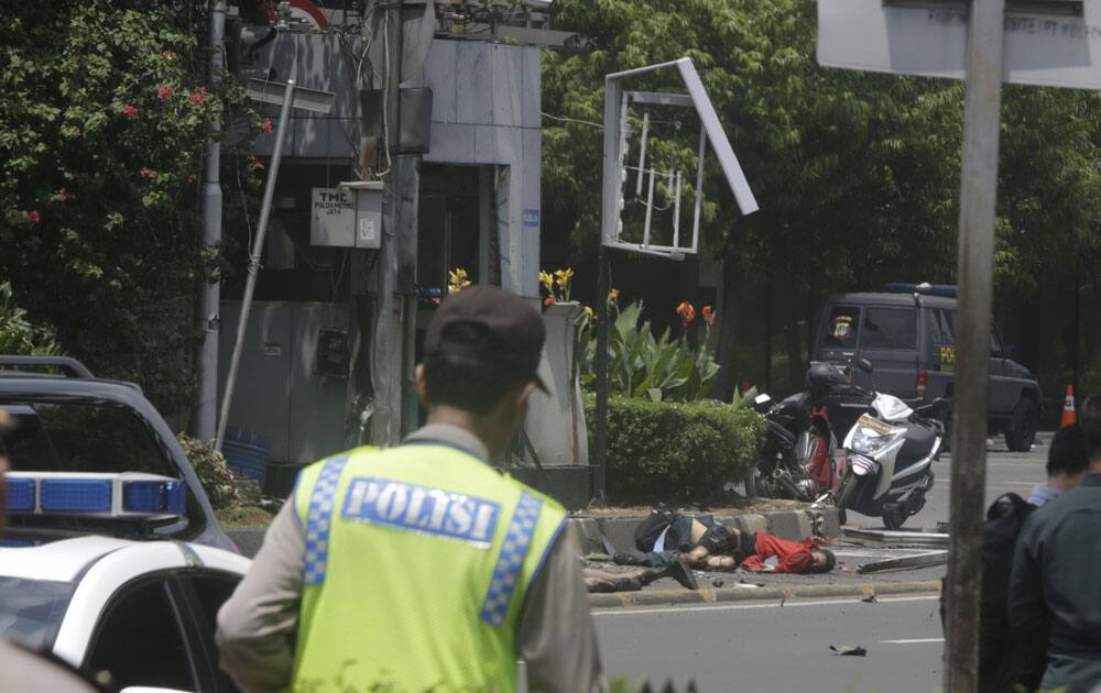 Bodies are seen as a police officer walks near the site where an explosion went off in Jakarta. 