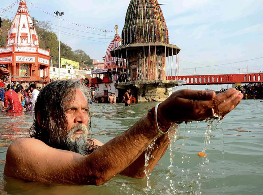 A sadhu performs prayers as he takes holy dip in River Ganges on the occasion of Makar Sankaranti in Haridwar.