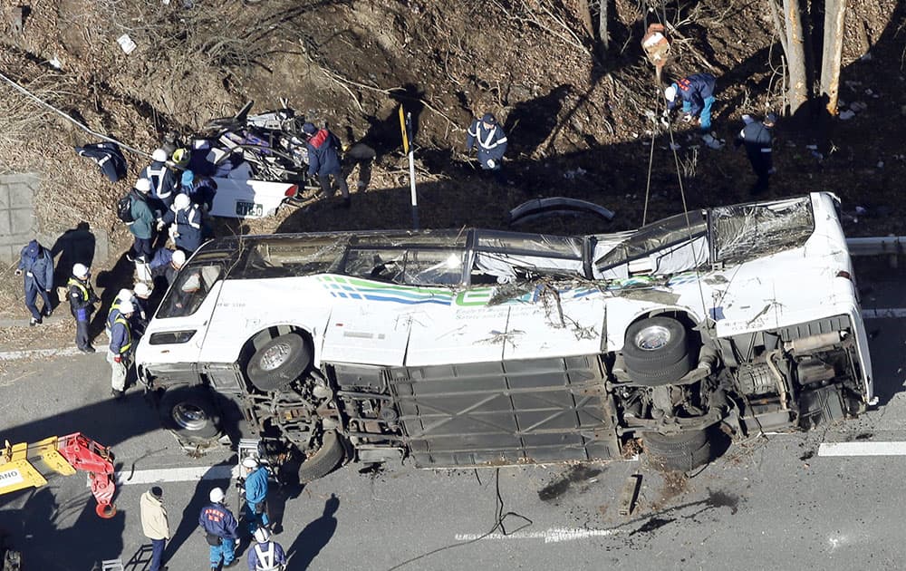 Investigators work near a damaged bus after it was transferred by crane onto a road in Karuizawa, Nagano prefecture, central Japan.
