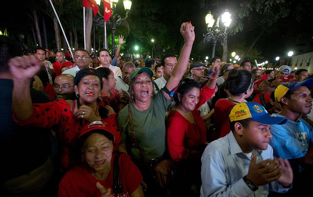 Government supporters look at Venezuela's President Nicolas Maduro during his the annual state of the nation report, on a television screen outside of the National Assembly in Caracas, Venezuela.
