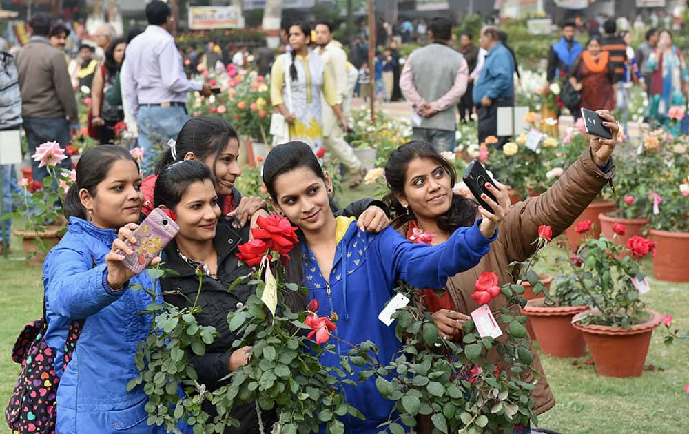 Girls take selfie with rose flowers during All India Rose Show in Bhopal.