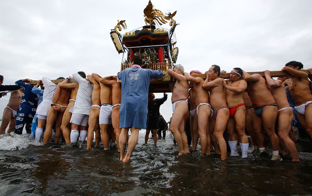 Participants carry a portable shrine while parading through the sea during a mid-winter festival at Enoshima beach in Fujisawa, west of Tokyo.