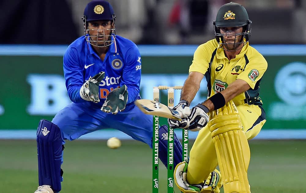 Australia's Glenn Maxwell, right, hits a reverse sweep watched by India's MS Dhoni during their one day international cricket match in Melbourne, Australia.
