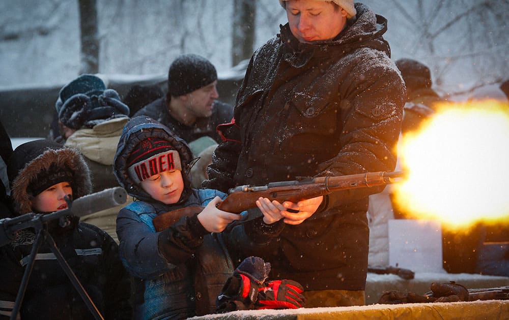 A military instructor helps a boy to shoot a rifle with blanks at a weapon exhibition during a military show in St.Petersburg, Russia.