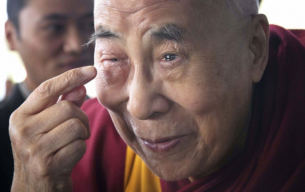Tibetan spiritual leader the Dalai Lama points to his swollen right eye as he talks to journalists before boarding his chartered flight in Dharmsala.
