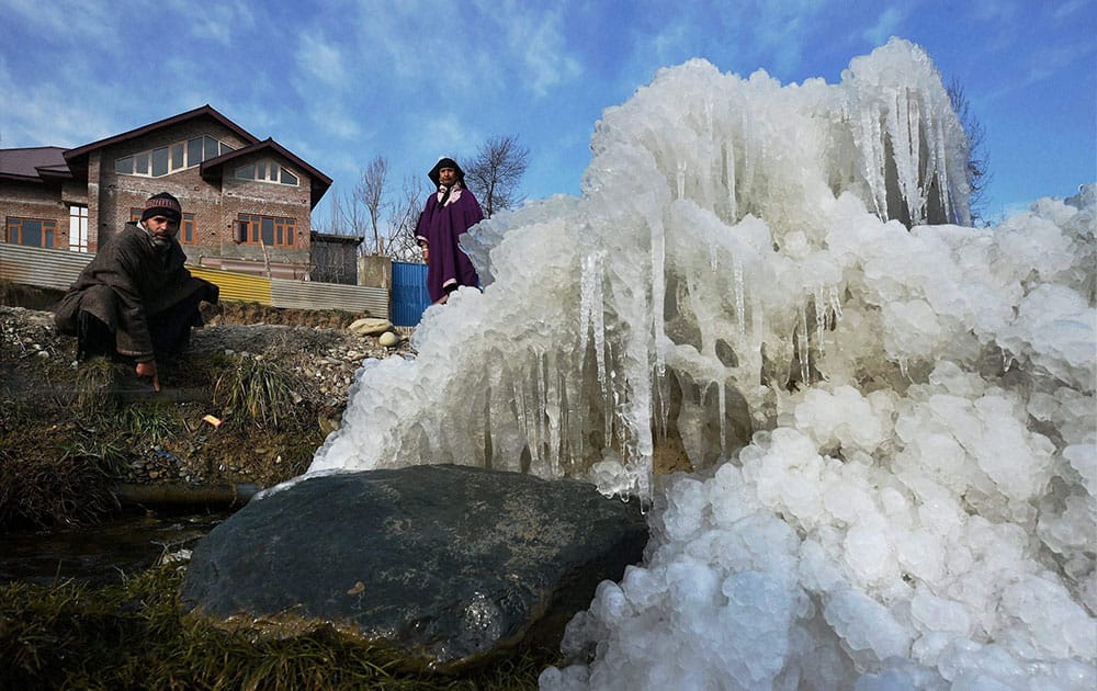 A man and a woman looking at the ice and icicles piled up on the rocks at Shopian in South Kashmir.