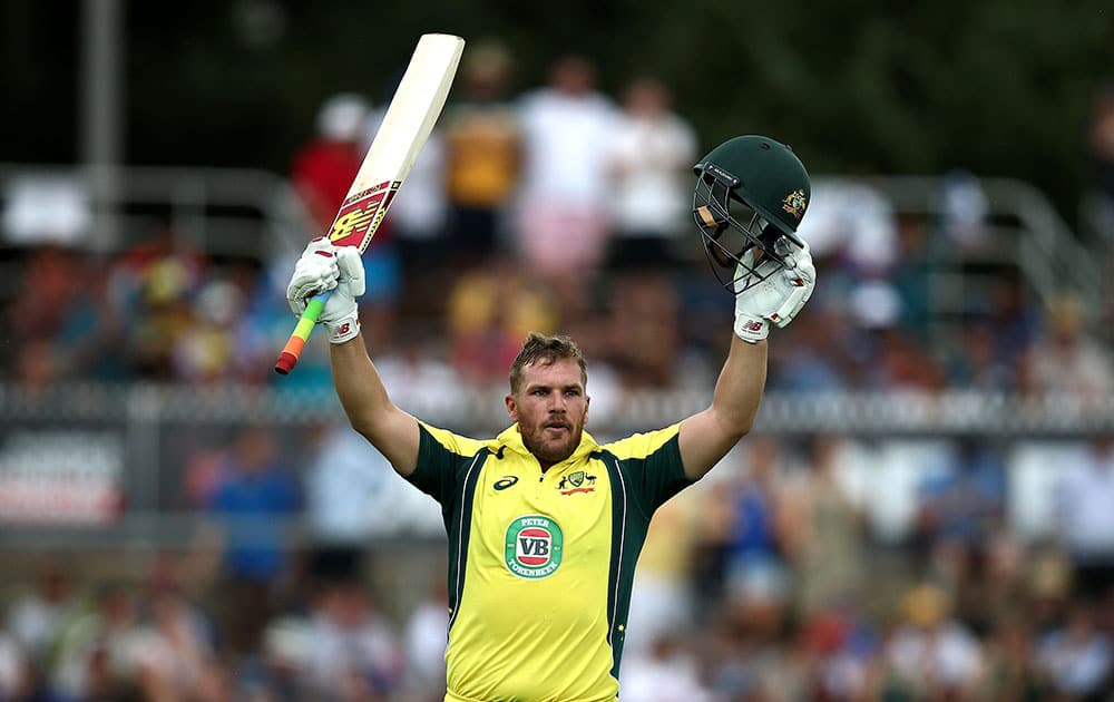 Aaron Finch puts his arms in the air as he celebrates hitting a century during a One Day International cricket match against India in Canberra, Australia.