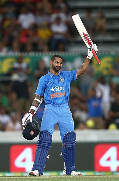 Shikhar Dhawan holds up his bat as he celebrates hitting a century against Australia during their One Day International cricket match in Canberra, Australia.