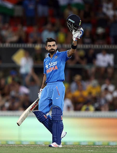 Virat Kohli holds up his helmet as he celebrates hitting a century against Australia during their One Day International cricket match in Canberra, Australia.