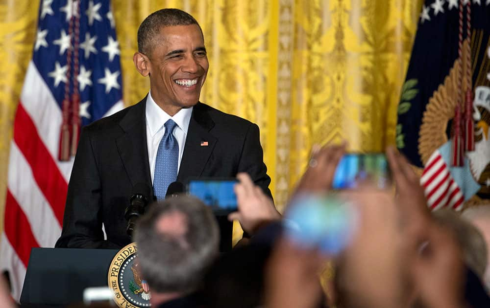 President Barack Obama smiles as he arrives to speak to mayors from around the country, in the East Room of the White House in Washington.