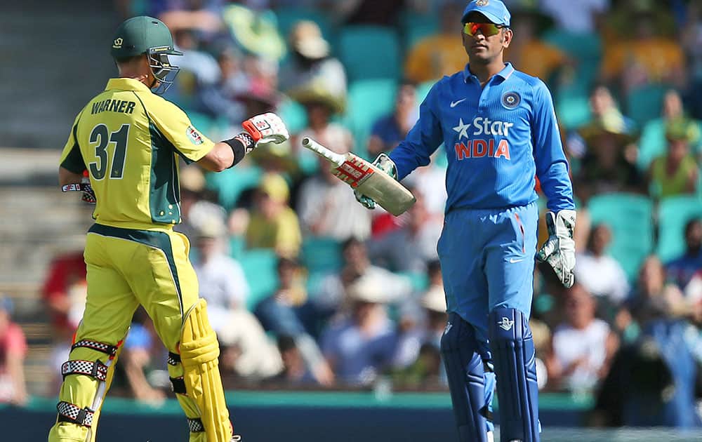 MS Dhoni returns a bat to Australia's David Warner after he lost grip of it while playing a shot during their one-day international cricket match in Sydney.