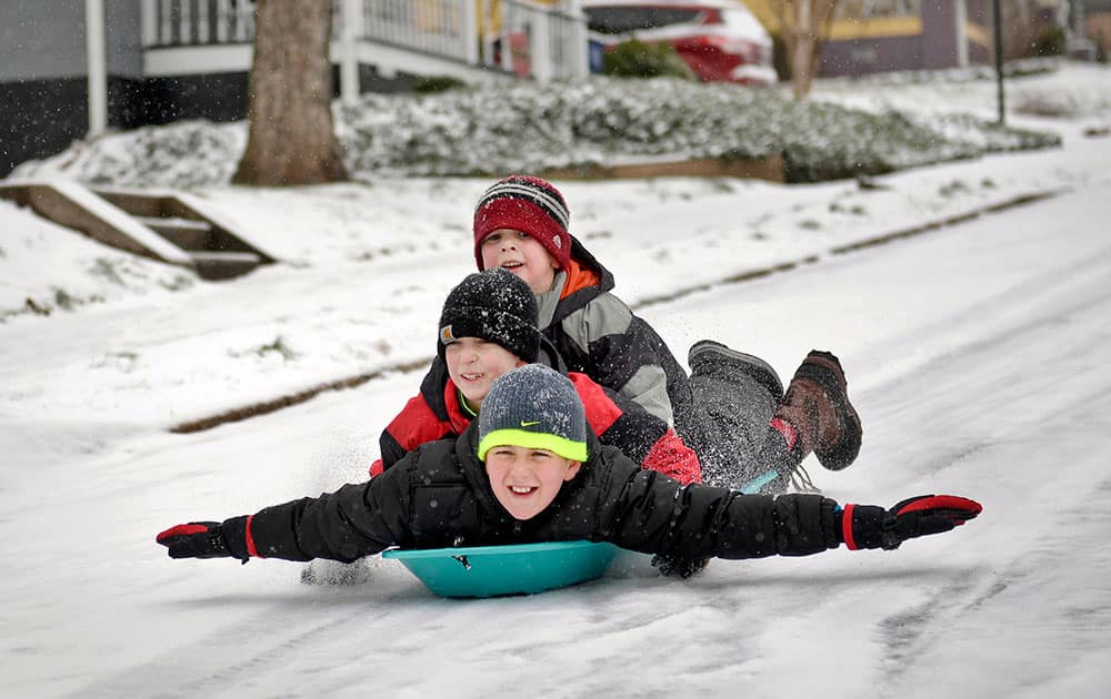 Stacked from bottom to top, Jack Parker, 9, Micah Wylde, 9, and Luke Wylde, 6, go sledding down their street, in Winston-Salem, N.C.