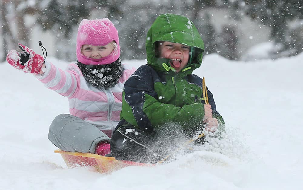 Harper Klein, 4, waves to her dad while sledding with Jonah Barge, 5, down Fifth Street in Roanoke, Va.