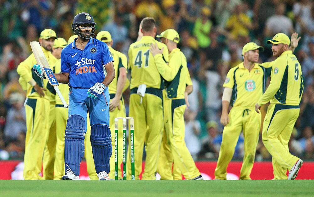 Australian team members celebrate as India's Rohit Sharma walks off the field after his wicket fell during their One Day International cricket match in Sydney.