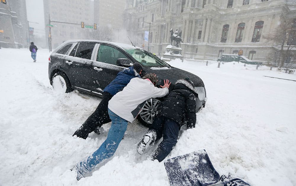 Good Samaritans help a stuck motorist in front of City Hall in Philadelphia as snow falls over the region.