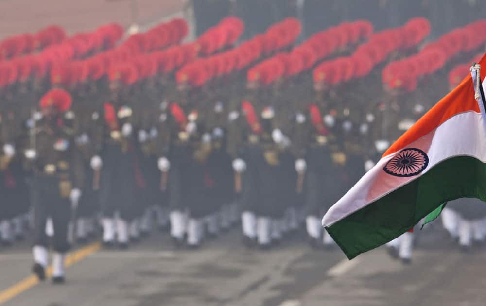 Indian flags flutter in the foreground as Indian security forces march during the Republic Day parade in New Delhi.
