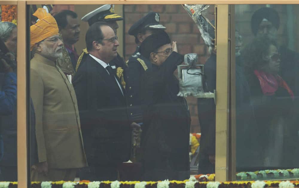 Indian Prime Minister Narendra Modi, left, and French President Francois Hollande, center, watch as Indian President Pranab Mukherjee salutes participants at the Republic Day parade in New Delhi. Hollande joined Modi and other top officials to view an elaborate display of Indian marching bands and military hardware as the guest of honor at India’s Republic Day celebration. 
