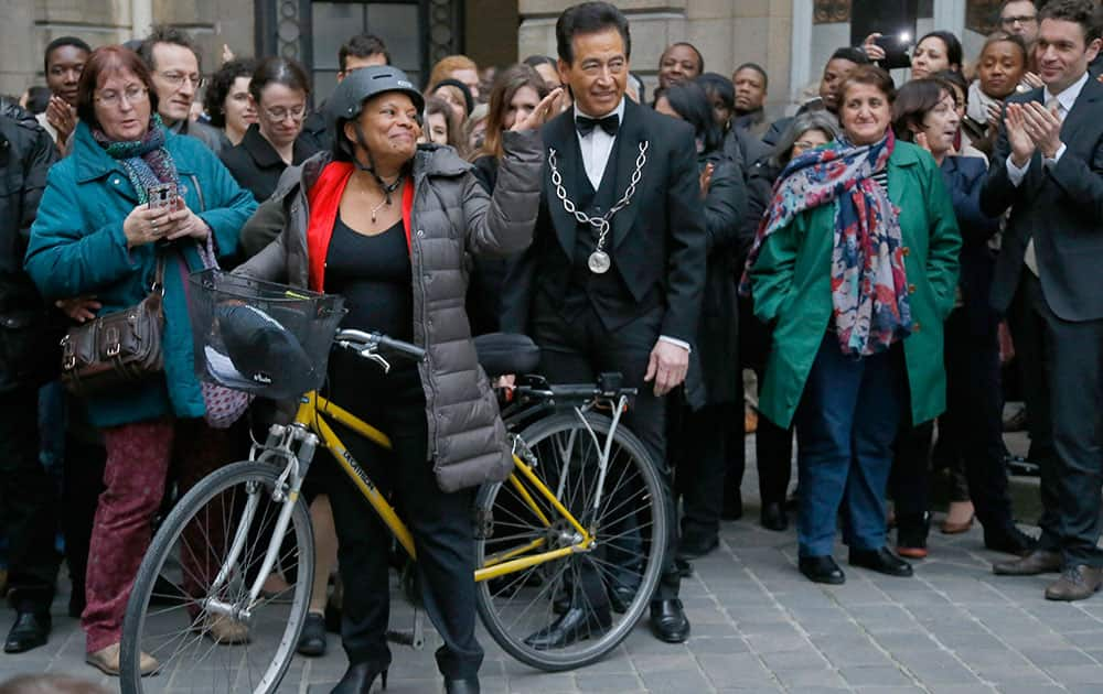 French outgoing Justice Minister Christiane Taubira waves prior to leaving the French Justice Ministry on a bike in Paris.