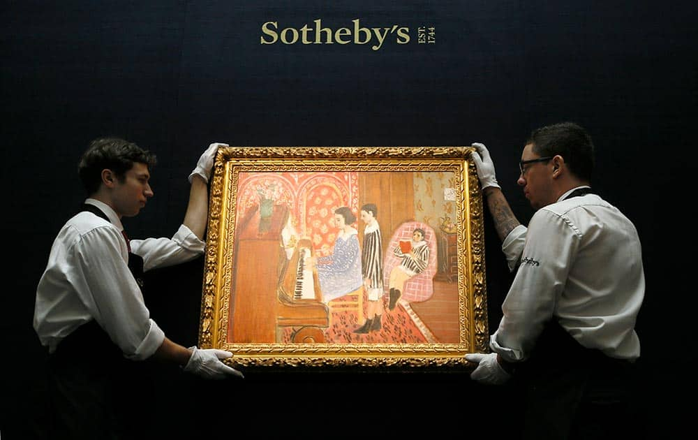 Sotheby's employees adjust a painting by Henri Matisse called 'La Lecon de Piano' at the auction rooms in London.