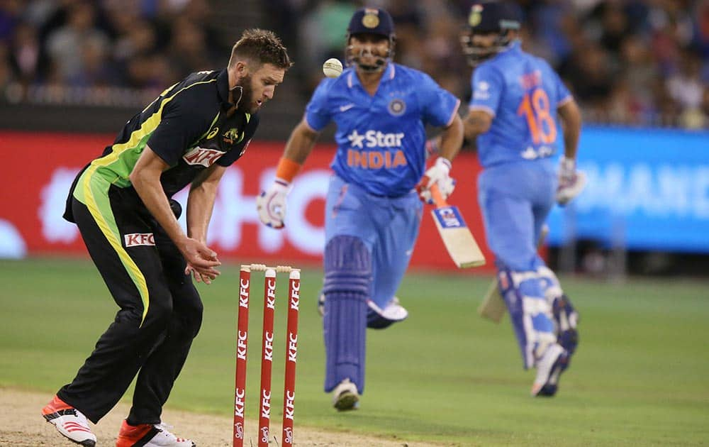 Virat Kohli, right, turns to see his teammate Suresh Raina saved from a run out as Australia's Andrew Tye, left, is unable to handle the ball at the stumps during their T20 Match against Australia in Melbourne.