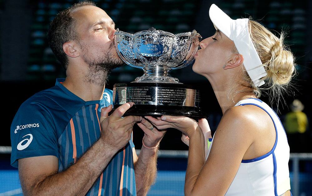 Elena Vesnina, right, of Russia and Bruno Soares of Brazil kiss their trophy after defeating Coco Vandeweghe of the United States and Horia Tecau of Romania in the mixed doubles final at the Australian Open tennis championships in Melbourne