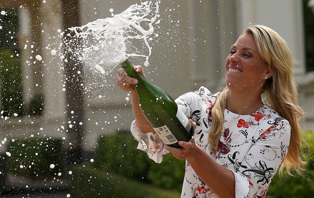Germany's Angelique Kerber sprays champagne at a photo shoot with her Australian Open trophy at Government House in Melbourne.