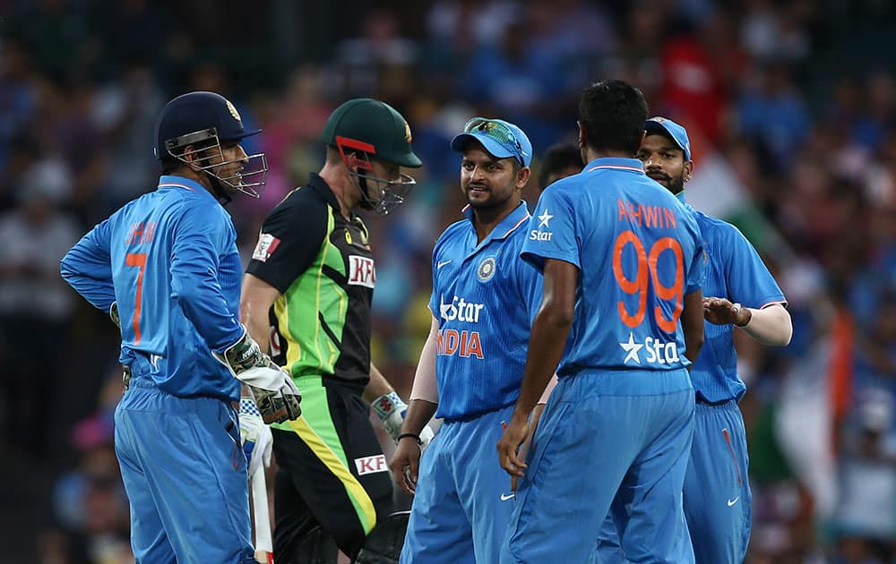 Indian bowler Ravichandran Ashwin right. celebrates with MS Dhoni, left, Australia's Shaun Marsh walks past during their T20 International cricket match in Sydney, Australia.