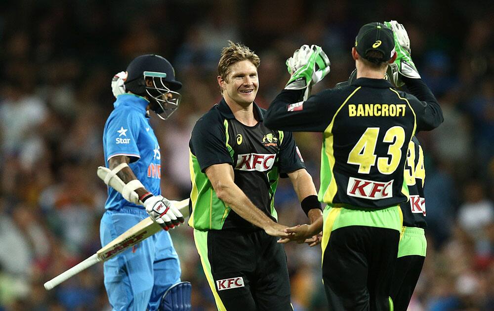 Australia's Shane Watson, center, celebrates with Cameron Bancroft right, after taking the wicket of India's Shikhar Dhawan during their T20 International cricket match in Sydney, Australia.