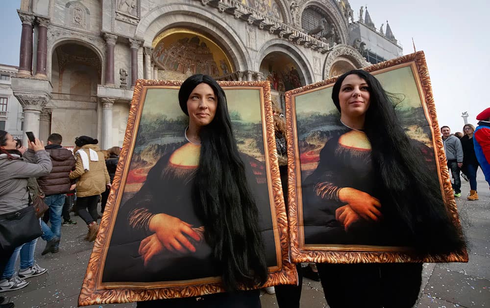 Two carnival revellers masquerade as Leonardo da Vinci's painting 'Mona Lisa' pose in St. Mark's Square in Venice, Italy.