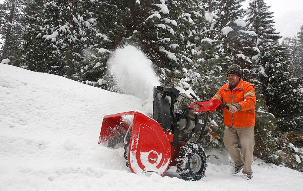 Michael Royere clears snow from a driveway near Strawberry, Calif.