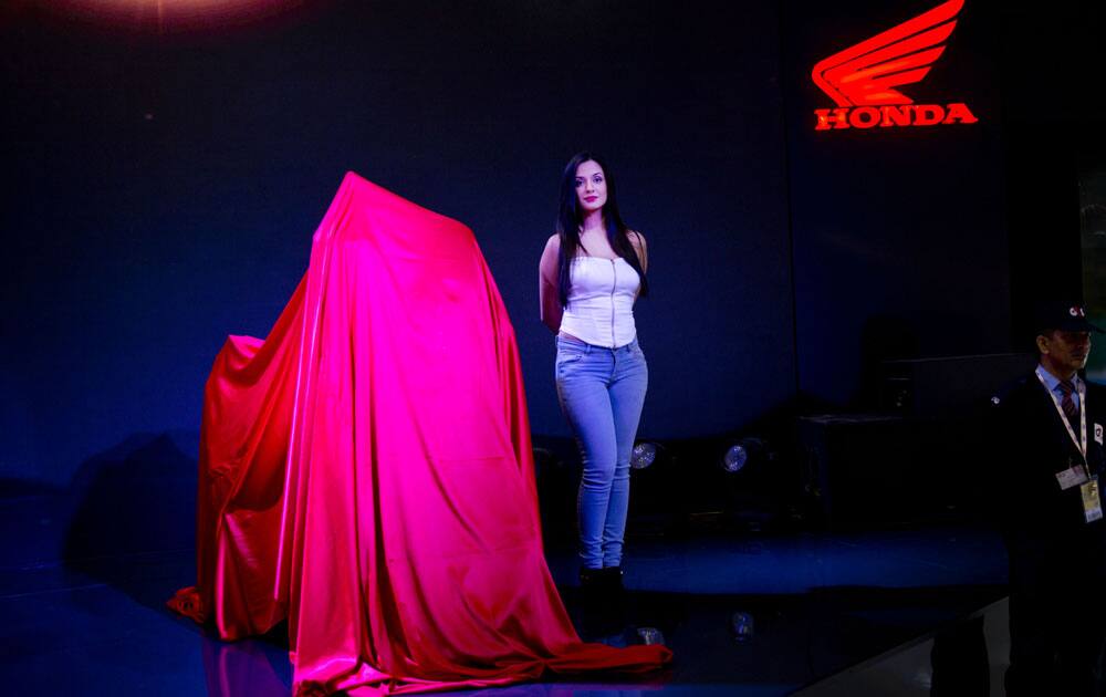 An Indian model stands next to soon to be launched Honda motorcycle at the Auto Expo in Greater Noida, near New Delhi, India , Wednesday, Feb. 3, 2016.