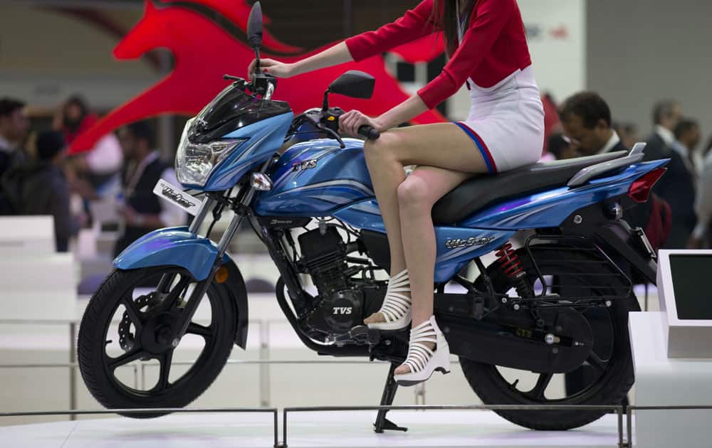 An Indian model sits on TVS victor motorcycle at the Auto Expo in Greater Noida, near New Delhi, India , Wednesday, Feb. 3, 2016.
