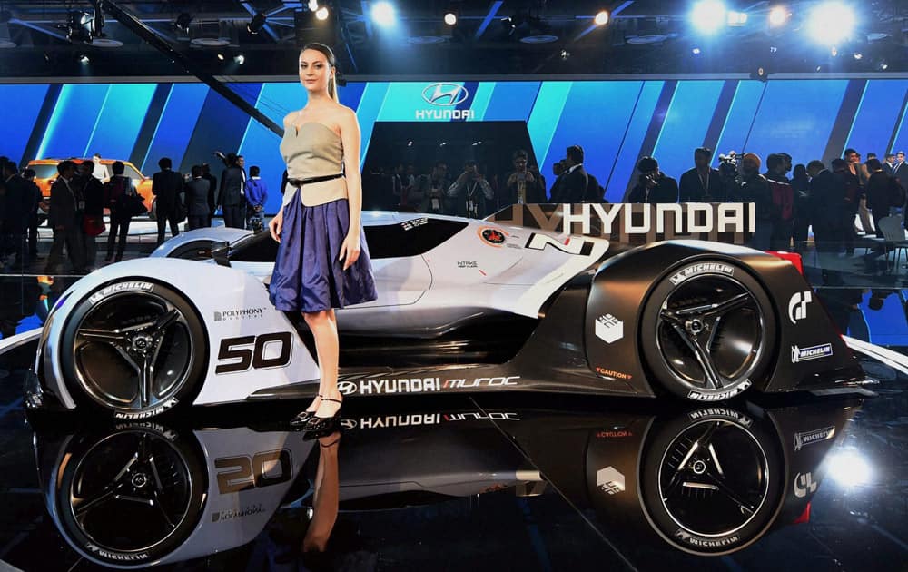 A model poses in front of a sports car displayed at the Hyundai stall at Auto Expo 2016 in Greater Noida.