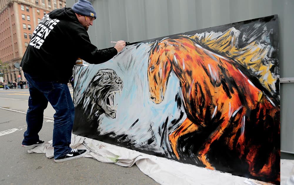 Kori Thompson works on a painting of a panther and a bronco at Super Bowl City in San Francisco.