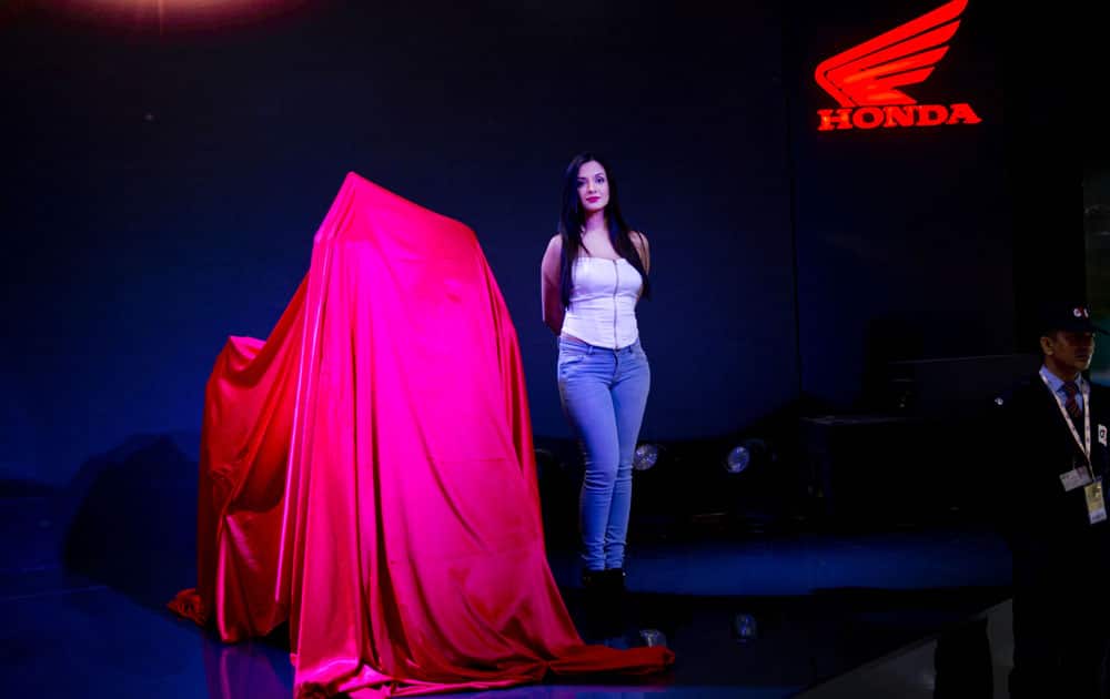 An Indian model stands next to soon to be launched Honda motorcycle at the Auto Expo in Greater Noida, near New Delhi, India , Wednesday, Feb. 3, 2016.
