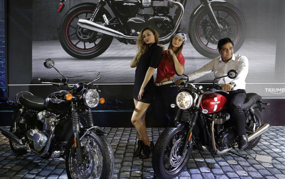 Models pose with Triumph's 900cc Street Twin, right, and Bonneville T120 motorcycles at the Auto Expo in Greater Noida.