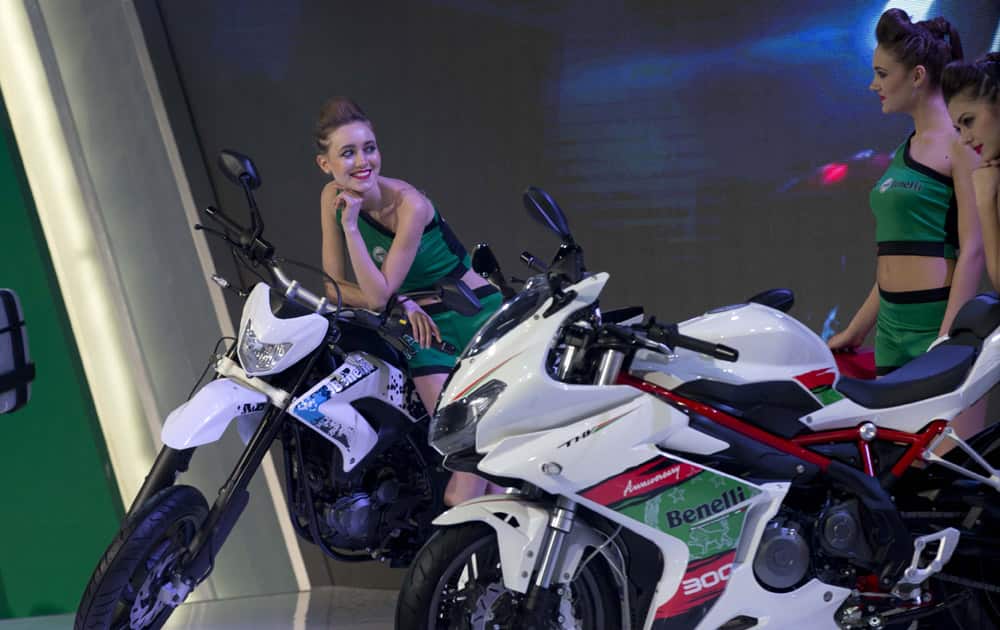 Indian and foreign models talk at the Benelli motorcycle counter at the press preview of Auto Expo in Greater Noida, near New Delhi.