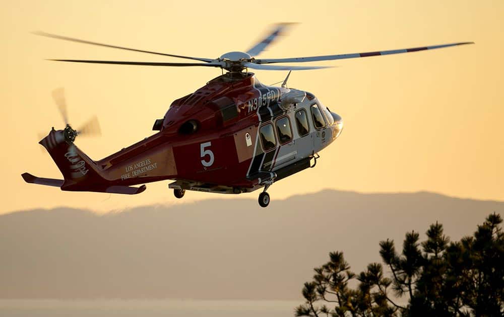 A Los Angeles County Fire helicopter gets ready to land at Angels Gate Park as rescue boats continue to search for wreckage from two small planes that collided in midair and plunged into the ocean off of Los Angeles harbor.