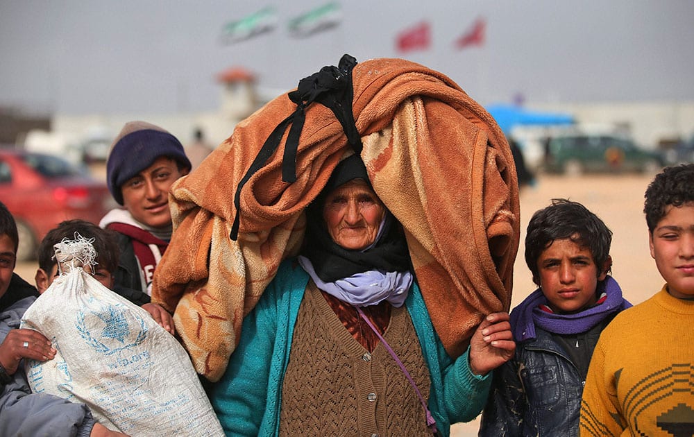 Syrians, some carrying belongings, head towards the Bab al-Salam border crossing with Turkey, in Syria.