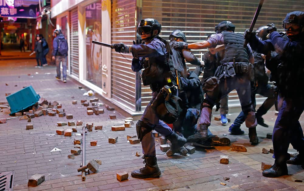 Riot police officers react as rioters set fires and throw bricks at them in Mong Kok district of Hong Kong.